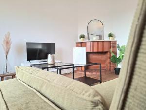 a living room with a couch and a table with a television at Le Sweet Escape - Vue Sur La Cathédrale in Beauvais