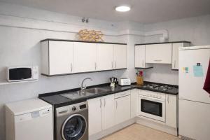 a kitchen with white cabinets and a washer and dryer at Apto Espert l PISCINA l Cine l Garaje l BBQ l Wifi in Biescas