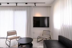 a living room with a couch and chairs and a tv at וילה לה מר - וילה עם בריכה ו-3 סוויטות מדהימות עם נוף לים המלח in Neve Zohar