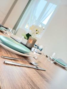a wooden table with silver utensils on it at Le Commercy - En Hyper Centre Et Très Spacieux in Beauvais