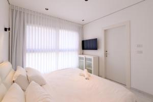 a white bedroom with a large bed with white pillows at וילה לה מר - וילה עם בריכה ו-3 סוויטות מדהימות עם נוף לים המלח in Neve Zohar