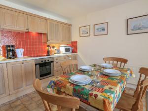 a kitchen with a table with chairs and a tablecloth on it at 3 The Salcombe in Salcombe