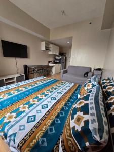 a bedroom with a large bed with a colorful blanket at SM Cebu City Sunvida Tower Condominium in Cebu City