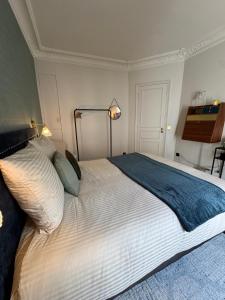 a bedroom with a large bed with white sheets at Maison Luxembourg - Chambre privée in Paris