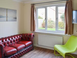 a living room with a red leather couch and a green chair at Sand Castles in Seahouses