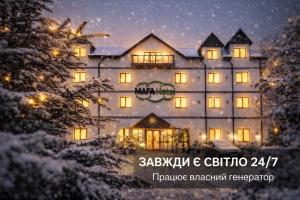 a large building with lights on in the snow at MAFA Hotel in Bukovel