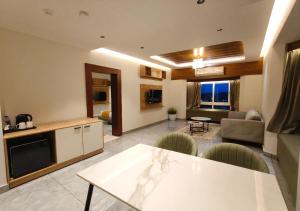 a kitchen and living room with a table and a couch at Mayo Suites in Palakkad
