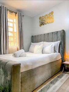 a bedroom with a large bed with white sheets at Graphite & Gold Suite in Ruiru