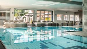 a large swimming pool with chairs in a building at Sporthotel Bernrieder Hof GmbH in Bernried