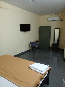 a room with a bed and a chair and a television at Nature's Frame Residency in Varkala