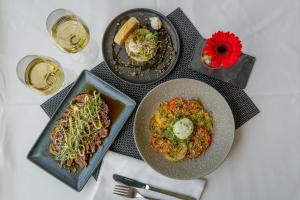 three plates of food on a table with glasses of wine at Leonardo Hotel Den Haag Babylon in The Hague