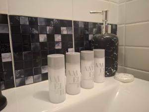 a bathroom sink with four tubes of klain products on it at Mansarda in Osijek +32 photos