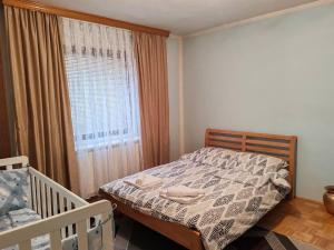 a bedroom with a bed and a window and a crib at Apartman Dačo in Vlasenica