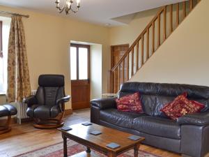 a living room with a leather couch and a chair at Bings Farm House in Whaley Bridge