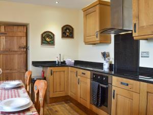 a kitchen with wooden cabinets and a table and a stove at Bings Farm House in Whaley Bridge