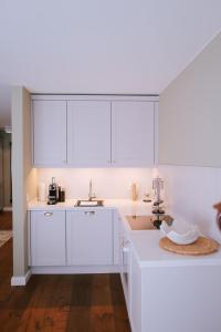 a white kitchen with white cabinets and a sink at Sünn un See - Hortensienblick in Ahrenshoop +8 photos