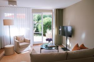 a living room with a couch and a tv and a chair at Sünn un See - Hortensienblick in Ahrenshoop
