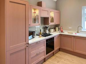 a kitchen with pink cabinets and a stove top oven at Pasture Barn in Barnard Castle
