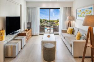 a living room with a couch and a tv at Pine Cliffs Gardens in Albufeira