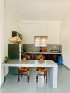 a kitchen with a large white table and two chairs at AQUARIUS Stay in Tangalle