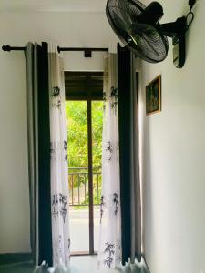 a room with a window with curtains and a fan at AQUARIUS Stay in Tangalle