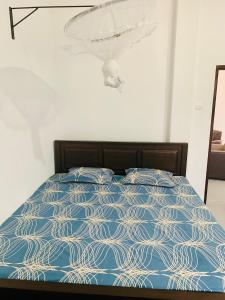 a bed with a blue comforter in a bedroom at AQUARIUS Stay in Tangalle