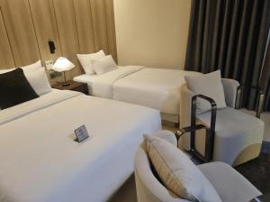 a hotel room with two beds and a chair at Hotel Signature Gwangju in Gwangju