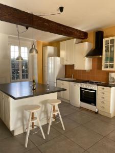 a kitchen with white cabinets and a black counter top at Guest House, Private Pool in LʼIsle-en-Dodon
