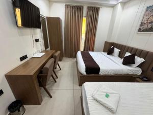 a hotel room with two beds and a desk at Gokul Dham in Haridwār