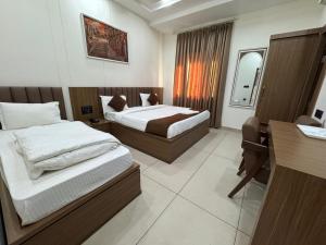a hotel room with two beds and a desk at Gokul Dham in Haridwār