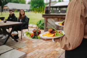 a person holding three plates of food on a patio at Hämsa Maheresto & Heaolukeskus in Võru +16 photos