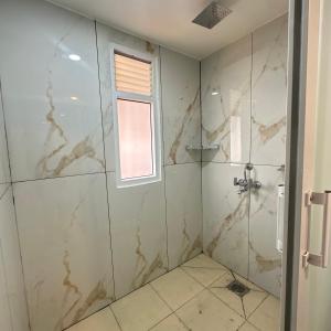 a bathroom with a shower with marble tiles at A Cube Homestay in Bharatpur