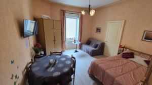 a bedroom with a bed and a table and a couch at Le sélect in Néris-les-Bains