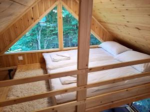 a bed in a wooden cabin with a window at Bear Watching Tiny House in Lupeni