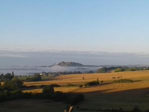 a field with cows grazing in a field with fog in the distance at Private gîte with stunning views & shared pool in Laussou