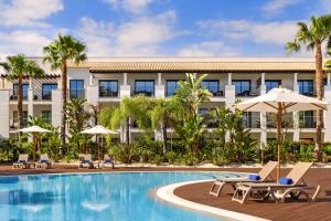 a hotel with a swimming pool with chairs and umbrellas at Pine Cliffs Gardens in Albufeira