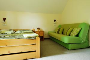 a bedroom with a green bed and a couch at Penzion Arosa in Růžová