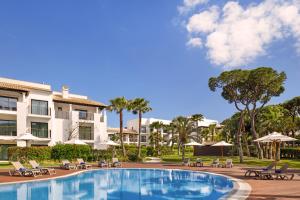a pool at a resort with chairs and umbrellas at Pine Cliffs Gardens in Albufeira