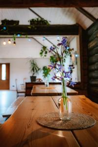a vase with purple flowers sitting on a wooden table at Hämsa Maheresto & Heaolukeskus in Võru