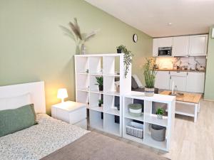a bedroom with a white book shelf and a kitchen at Dunes Trail 2 in Melnragė