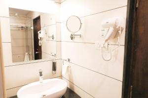 a white bathroom with a phone and a sink at The White Pearl Suites in Bangalore
