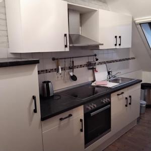 a kitchen with white cabinets and a sink at Darpvenner Diele in Ostercappeln