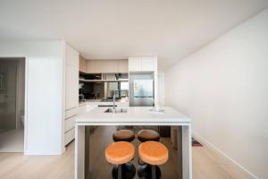 a kitchen with a island with two stools at Queens Wharf 1B plus Study apt - level 29 City view in Brisbane +11 photos