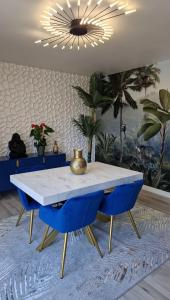 a dining room with a white table and blue chairs at Le Peekskill in Montbron