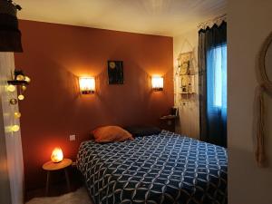 a bedroom with a bed and two lights on the wall at Maisonnette dans son écrin de verdure in Saint-Geniez-dʼOlt