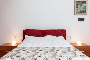 a bed with a red headboard and two lamps on tables at Villetta Degli Aranci in San Foca