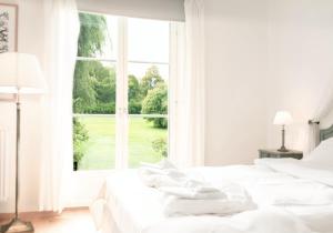 a white bedroom with two beds and a large window at Wiks Slott in Vik