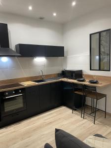 a kitchen with black cabinets and a table with chairs at Cozy Studio with Terrace in Cers