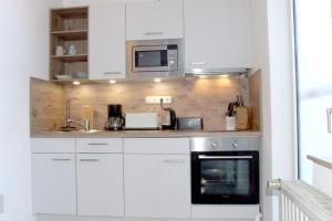 a kitchen with white cabinets and a microwave at Hotel und Gasthaus Sieling in Liebenau