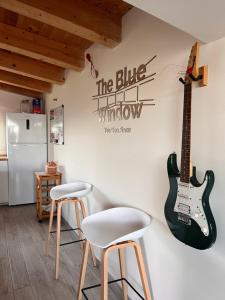 a kitchen with two stools and a guitar on the wall at The Blue Window - Apartment - 300m from sea in Augusta